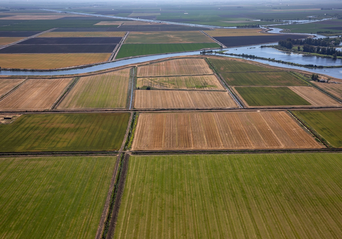 An irrigation canal runs through a patchwork of farmland near the confluence of the Sacramento and San Joaquin Rivers as viewed from the air near Lodi, California